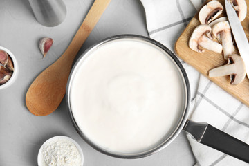 Flat lay composition with delicious creamy sauce on grey table