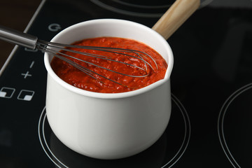 Cooking delicious tomato sauce in pan on stove, closeup