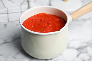 Delicious tomato sauce in pan on marble table