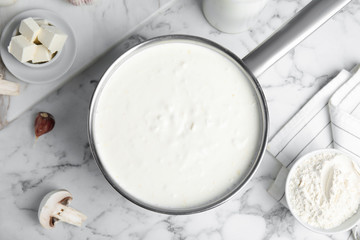 Delicious creamy sauce in pan on marble table, flat lay