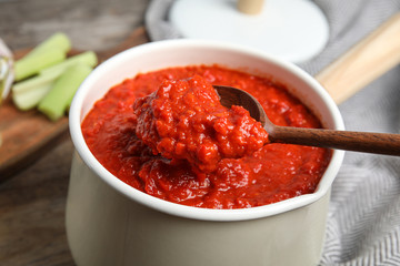 Spoon and pan with delicious tomato sauce, closeup view