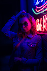 Sexy portrait of a young girl with an open bust in sunglasses and with in the night city, with...
