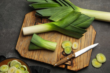 Flat lay composition with fresh raw leek on dark grey table. Ripe onion
