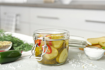 Jar with pickled cucumbers on grey table in kitchen