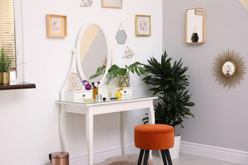 Stylish room interior with modern dressing table near light wall