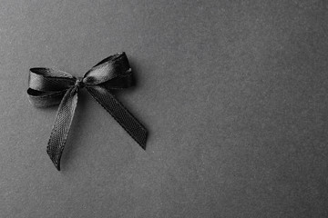 Black ribbon bow on dark background, top view with space for text. Funeral symbol
