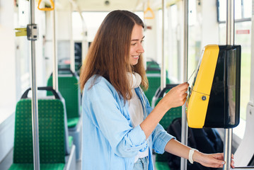 Young woman pays by bank card for the public transport in the tram or subway.