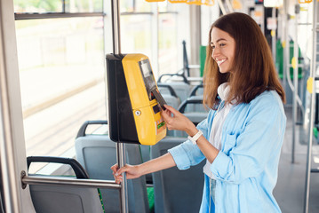 Young woman pays by bank card for the public transport in the tram or subway.