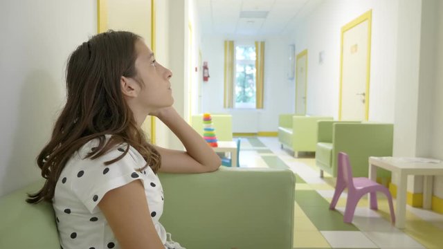 the girl is sitting in the lobby of the children's clinic, waiting for an appointment with the doctor. concept of medical examination, health monitoring, preventive examination of doctors.
