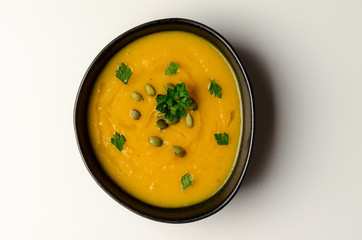 Pumpkin soup with pumpkin seeds on white background. top view