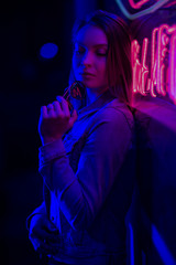 Fototapeta na wymiar creative sexual portrait of a girl in neon lighting with glasses, night party, dancing, game business, striptease