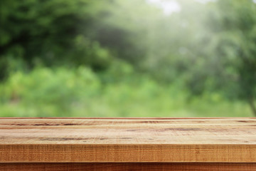 Blurred abstract green bokeh of garden and wooden table background.