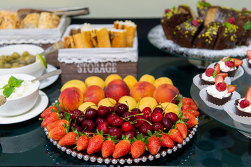 Fototapeta na wymiar Healthy fruit platter, strawberries cherries oranges peaches apples apricots on the table, close up