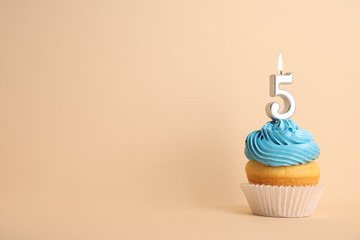 Birthday cupcake with number five candle on beige background, space for text