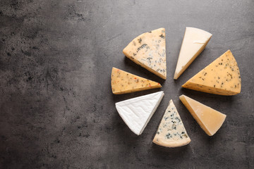 Flat lay composition with different kinds of cheese on grey background, space for text