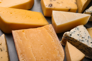 Different kinds of delicious cheese on stone background, closeup