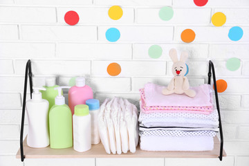 Baby accessories on shelf near white brick wall