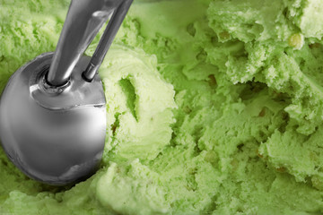 Delicious pistachio ice cream with scoop as background