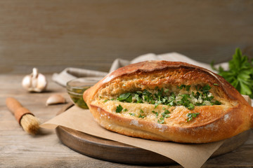Delicious homemade garlic bread with herbs on wooden table