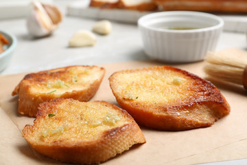 Slices of delicious toasted bread with garlic on table, closeup