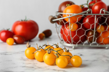 Branch of yellow cherry tomatoes on marble table
