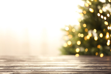 Empty table and blurred fir tree with yellow Christmas lights on background, bokeh effect. Space...
