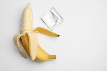 Banana with condom on white background, top view. Safe sex