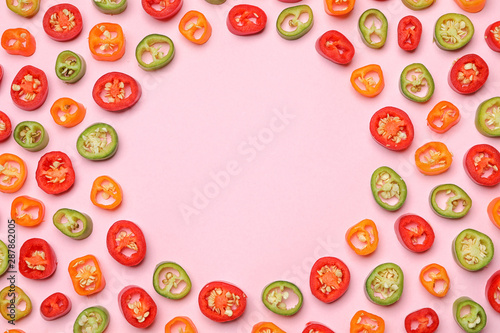 Frame made with different cut chili peppers on pink background, flat lay. Space for text