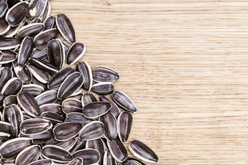 Dry sunflower seeds on wooden background with copy space. Seeds with peel on table. Top view.