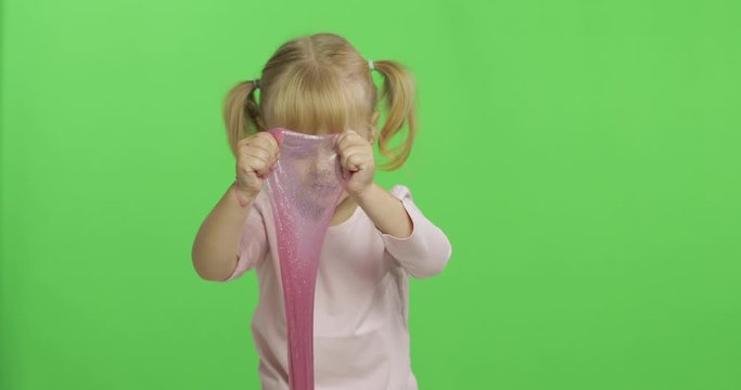 Kid playing with hand made toy slime. Child having fun making pink slime