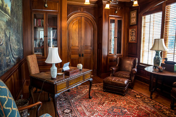 Dark stained wood stained home office with warm rust desert color with wood furniture, desk, lamp...