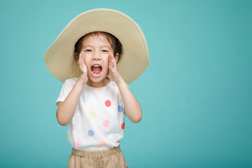 Excited Asian little girl is announcing telling a secret or shouting, empty space in studio shot...
