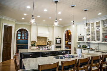 large kitchen with eat-in dining at spacious granite countertop and barstools. Pendant lighting and open kitchen layout.
