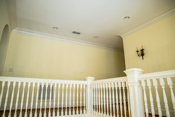 interior painted white ornate banister with yellow walls in an upstairs of a home with balcony view