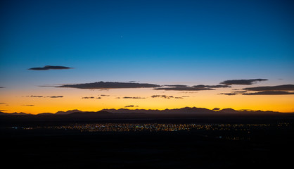 Cityscape with the city lights of Uyuni at sunset located in the altiplano near the salt flats with the Andes mountain range in the background, Bolivia.