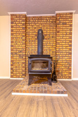 Fireplace inside the room of a home with wood floor and stone brick accent wall