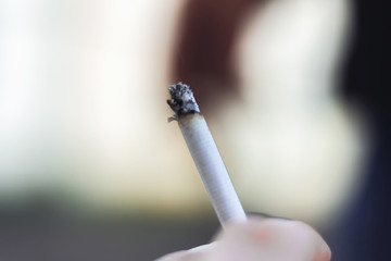 Young man's hand holding a cigarette with smoke