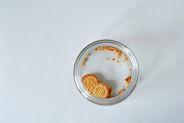  Glass jar with cookie leftovers and crumbs over white