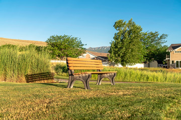 Empty outdoor bench on a grassy ground with hill and blue sky in the background