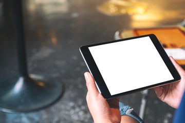 Mockup image of a woman sitting and holding black tablet pc with blank white desktop screen