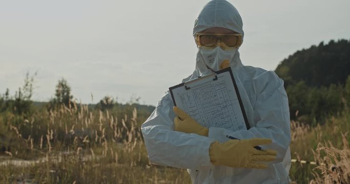 Male ecologists working at polluted swamp landscape. Close-up excited scientist writing notes then dancing of joy on camera enjoying summer evening.
