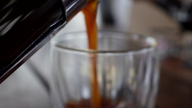 Pouring newly pressed coffee in slow motion into glass