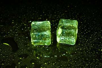 Green ice cubes on black table background.