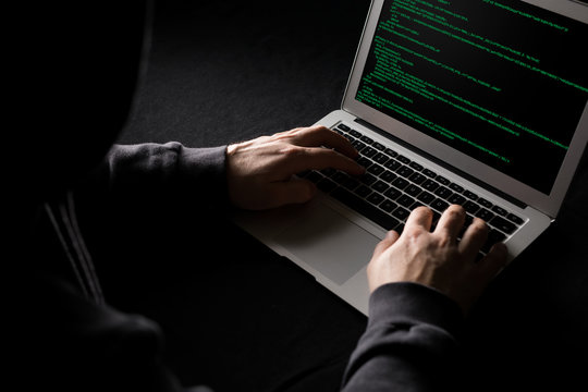 Hacker working on computer code in the dark
