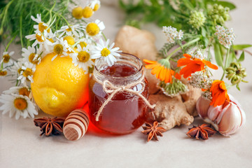 Jar of organic honey, lemon, garlic root, anise, fresh flowers camomile and calendula. Concept of alternative medicine, homeopathy, seasonal flu hot tea, remedy of colds