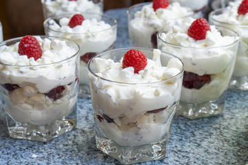 Making fresh cream dessert in glasses with fresh raspberries