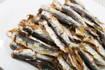 Dish of  many tasty baked in oven anchovy served on plate at table