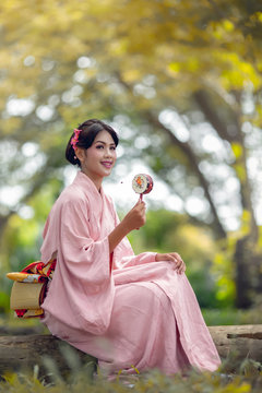 Asian girls wear kimonos. Which is a very popular national dress of Japan. She is playing toys in the middle of the forest, change color season.