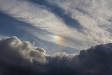 Fototapeta na wymiar Rainbow colored sundog in cloudy blue sky