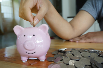 Woman hand putting coin on piggy bank. Saving maney concept.
